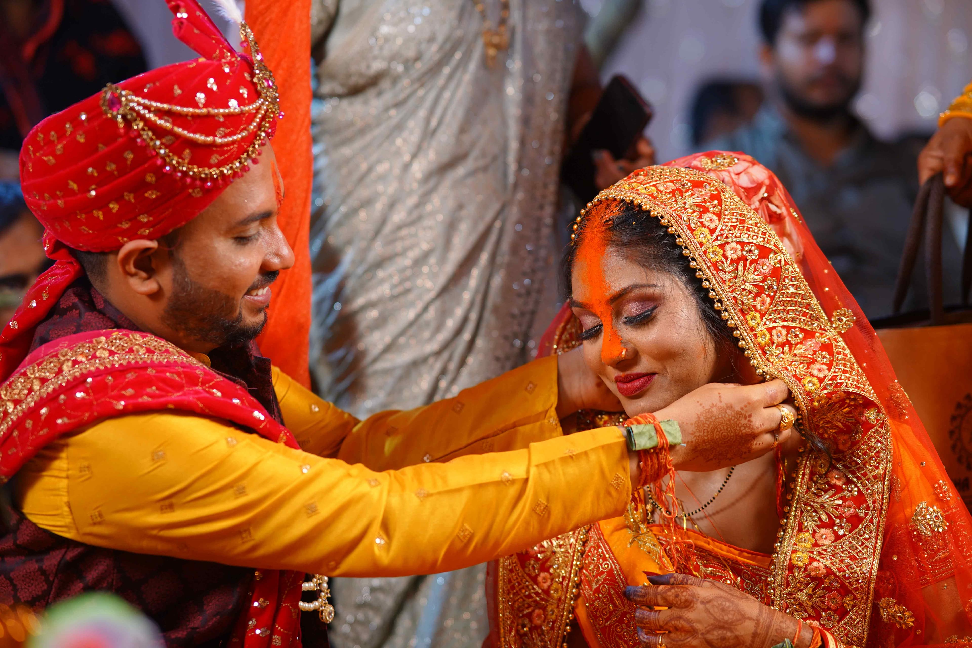 A groom gently placing a mangalsutra around the bride's neck, symbolizing their love and commitment to each other 