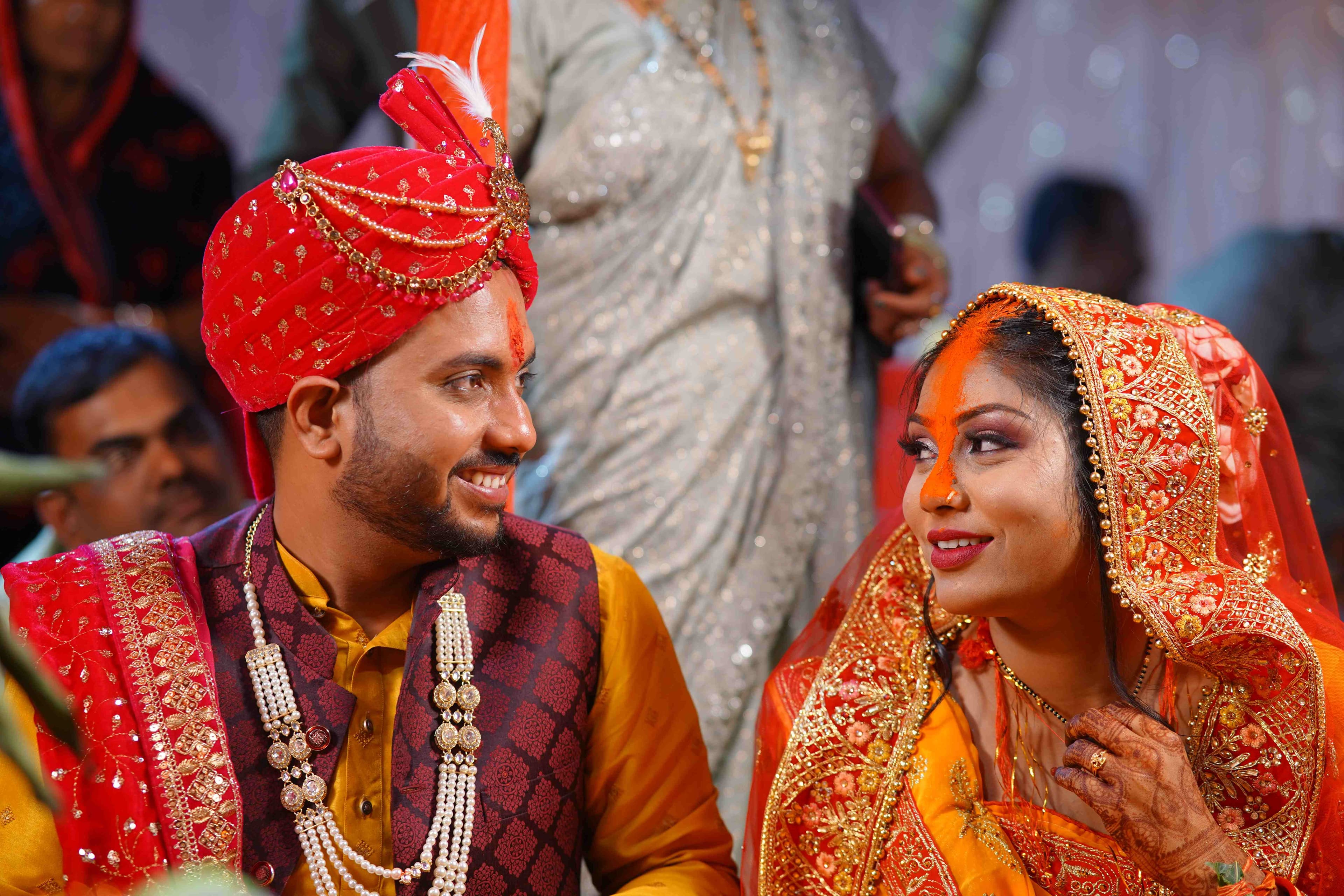 A joyful bride and groom dressed in vibrant traditional Indian attire, radiating love and happiness on their special day